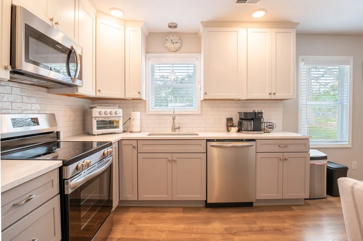 A modern kitchen featuring stainless steel appliances, white cabinetry, and broad countertops bathed in natural light from a window. The space is ready for meal prep, family gatherings, and entertaining.