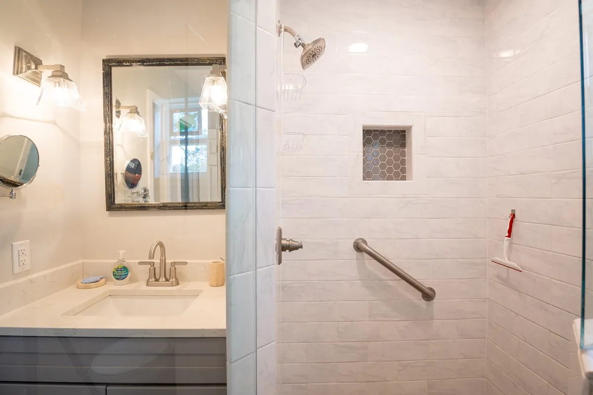 A tranquil bathroom showcasing a spacious shower area, modern vanity, large mirror, and calming lighting. The overall atmosphere is soothing, perfect for relaxation and self-care.