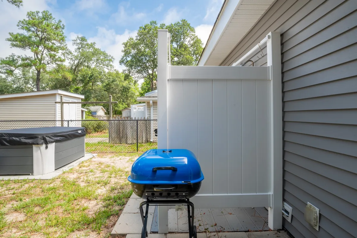 This image features a bold blue grill set in a playful outdoor space framed by a clean white fence. The area is ready for barbecuing or enjoying summer evenings, echoing the vibrant, communal spirit described in the section.