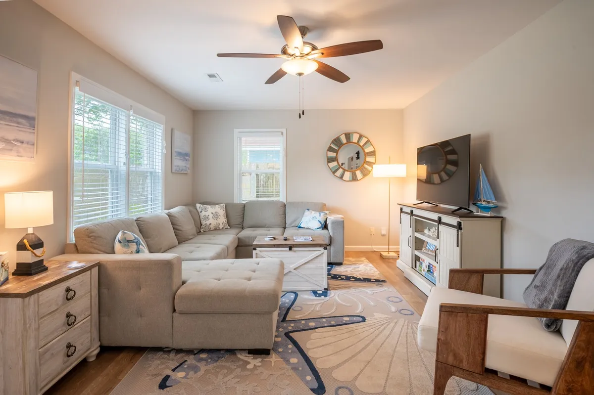A comfortable and inviting living room featuring a sofa, coffee table, TV, lamp, and decorative wall art. The space exudes warmth and is arranged for easy movement, emphasizing a single-level layout ideal for all guests.